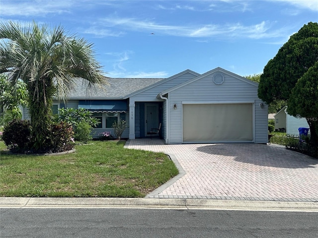 ranch-style home with a garage, a front yard, decorative driveway, and roof with shingles