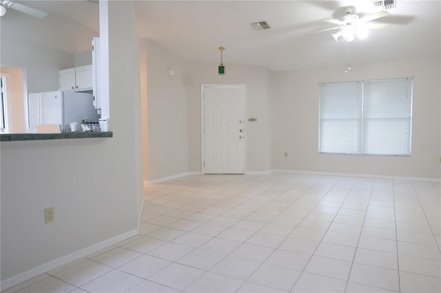 interior space featuring light tile patterned floors, ceiling fan, visible vents, and baseboards