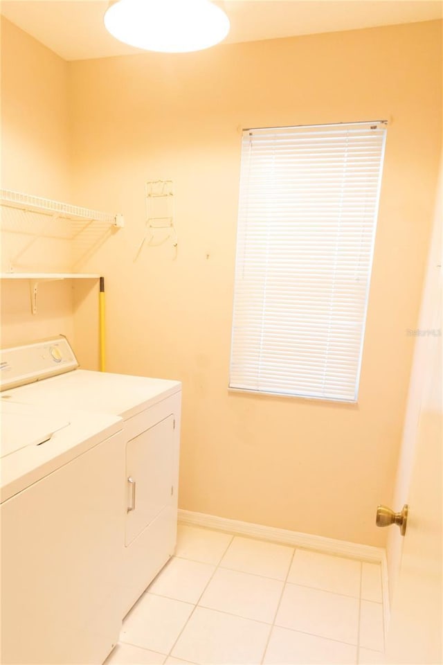 clothes washing area with laundry area, light tile patterned floors, baseboards, and washing machine and clothes dryer