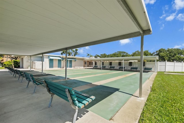 view of home's community with shuffleboard, a lawn, and fence