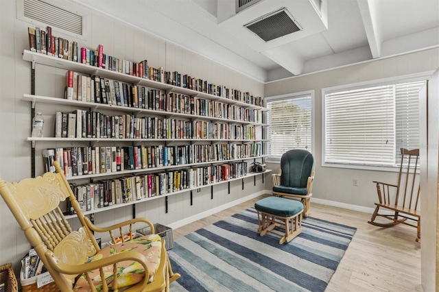living area featuring baseboards, beamed ceiling, wood finished floors, and visible vents