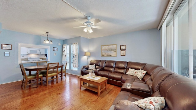 living room featuring light hardwood / wood-style flooring, a textured ceiling, and ceiling fan with notable chandelier