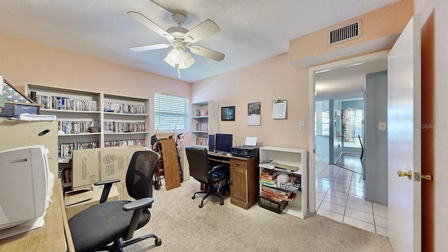 carpeted office space with a textured ceiling and ceiling fan