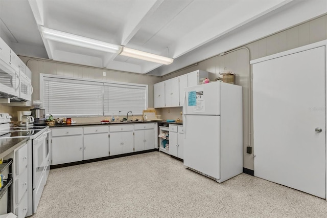 kitchen featuring dark countertops, light speckled floor, a sink, white appliances, and white cabinetry