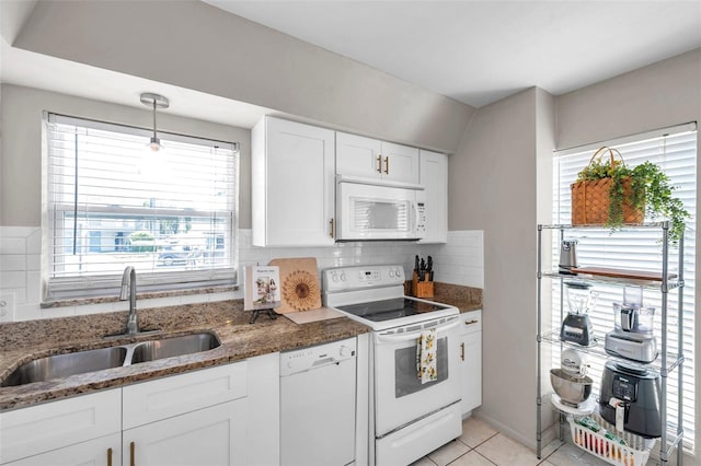 kitchen with decorative backsplash, a sink, white cabinets, dark stone counters, and white appliances