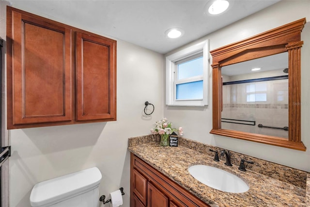 bathroom with vanity, a shower with door, and toilet