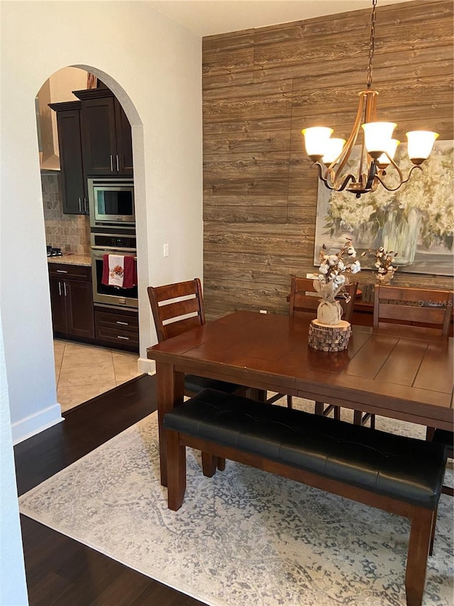 dining room with a chandelier and wooden walls