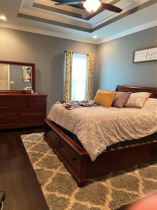 bedroom featuring ceiling fan, a raised ceiling, crown molding, and dark wood-type flooring