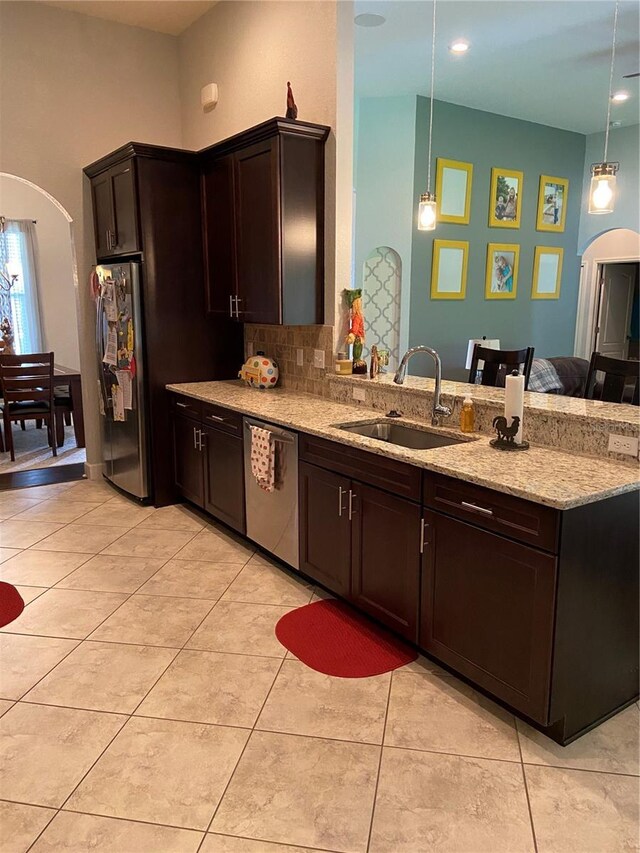 2875 Creeks Crossing Blvd, Lakeland, FL 33810 - kitchen with dark brown cabinets, a sink, a peninsula, arched walkways, and stainless steel appliances