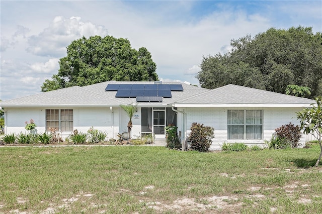 ranch-style home featuring a sunroom, solar panels, and a front yard