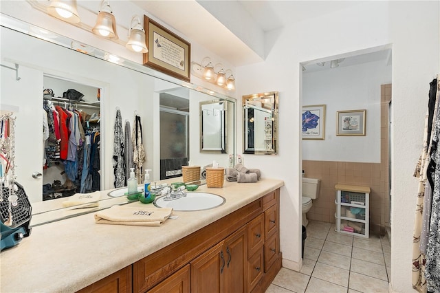 bathroom featuring tile patterned flooring, an enclosed shower, toilet, vanity, and tile walls