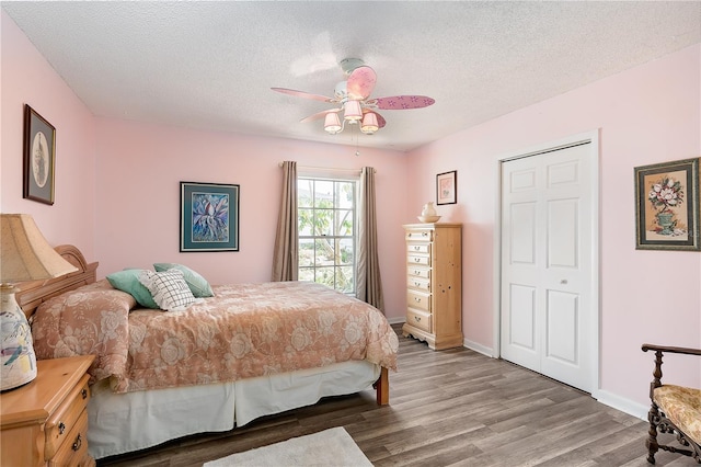 bedroom with ceiling fan, wood-type flooring, a textured ceiling, and a closet