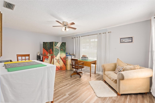 interior space featuring a textured ceiling, light hardwood / wood-style floors, and ceiling fan