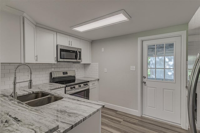 kitchen with light stone counters, sink, white cabinets, and appliances with stainless steel finishes