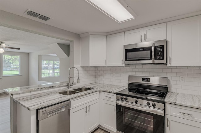 kitchen with kitchen peninsula, stainless steel appliances, white cabinetry, and sink