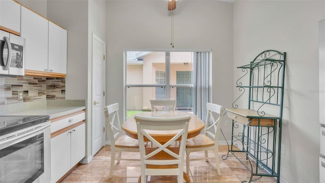 kitchen featuring tasteful backsplash, electric range, and white cabinets