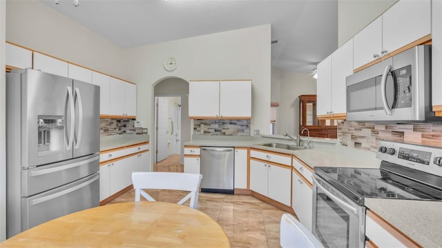 kitchen with tasteful backsplash, sink, white cabinets, and appliances with stainless steel finishes