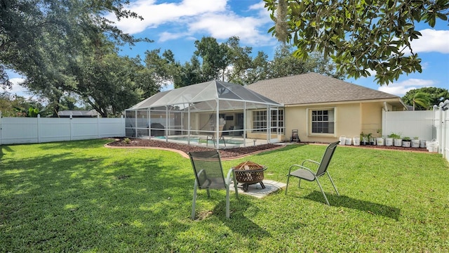 back of property featuring a fenced in pool, a fire pit, and a yard