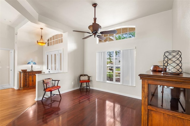 living area with a ceiling fan, baseboards, a towering ceiling, and wood finished floors