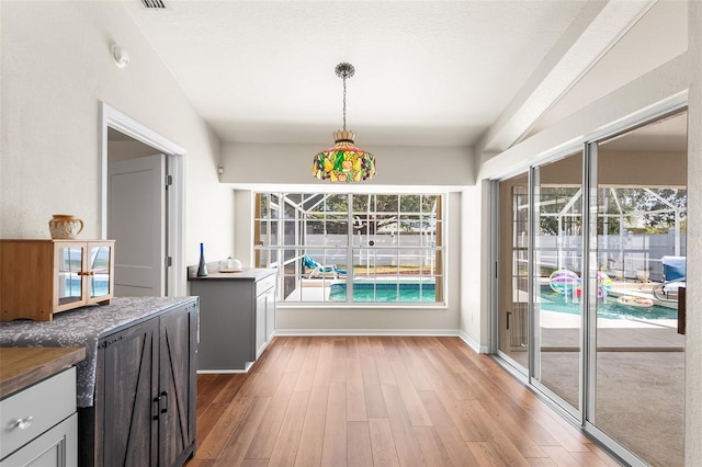 unfurnished dining area featuring baseboards, light wood-style floors, and visible vents