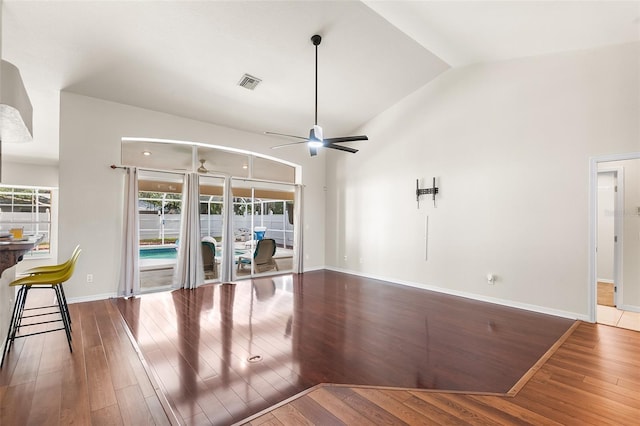 unfurnished living room with a ceiling fan, lofted ceiling, baseboards, wood-type flooring, and visible vents