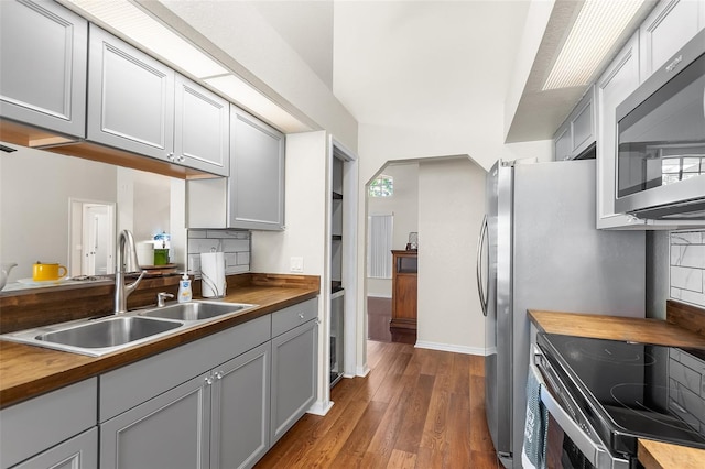 kitchen featuring stainless steel microwave, a sink, gray cabinets, butcher block counters, and electric range oven