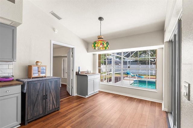 dining room with vaulted ceiling, visible vents, wood finished floors, and baseboards