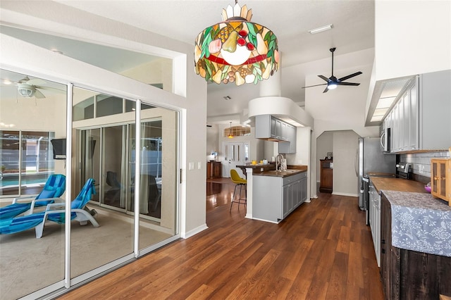 kitchen featuring a ceiling fan, dark countertops, a sink, and dark wood-style floors