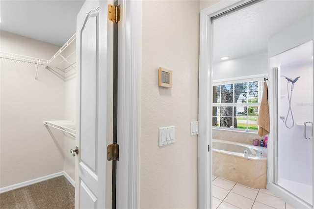 full bath with a garden tub, a shower stall, a spacious closet, and a textured wall