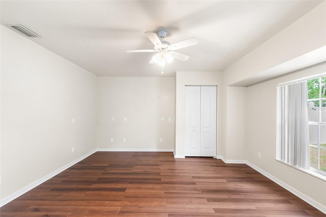 unfurnished bedroom with wood finished floors, a closet, visible vents, baseboards, and ceiling fan