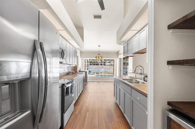 23338 Duchess Ave, Port Charlotte, FL 33954 - kitchen featuring appliances with stainless steel finishes, light wood-type flooring, gray cabinetry, light countertops, and decorative light fixtures