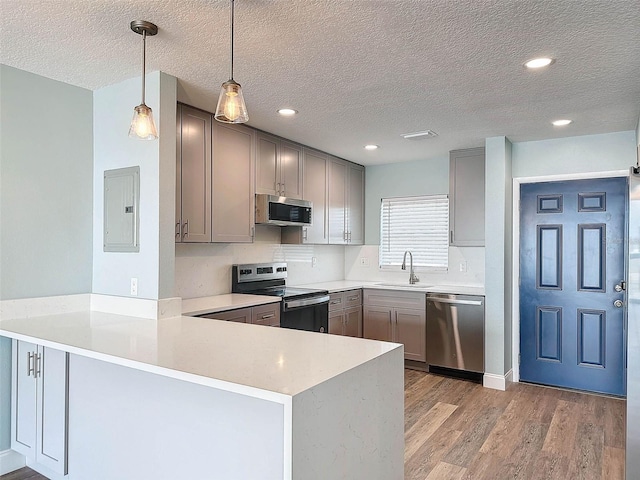 kitchen with light hardwood / wood-style flooring, stainless steel appliances, gray cabinets, kitchen peninsula, and pendant lighting