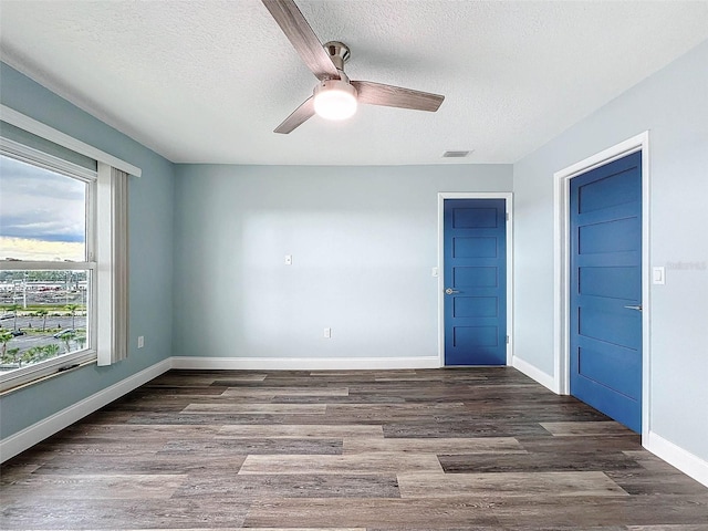 unfurnished bedroom featuring ceiling fan, a textured ceiling, and dark hardwood / wood-style floors