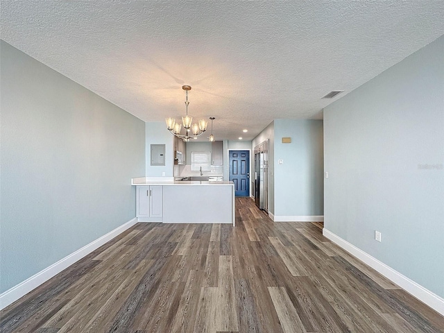 unfurnished living room with a textured ceiling, a chandelier, and dark wood-type flooring