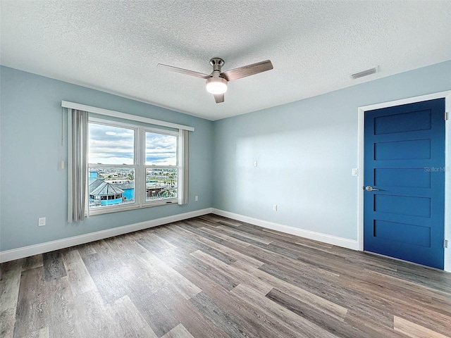 empty room with a textured ceiling, ceiling fan, and hardwood / wood-style floors