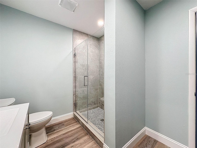 bathroom with a shower with shower door, hardwood / wood-style flooring, vanity, and toilet