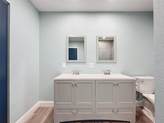 bathroom featuring dual vanity, wood-type flooring, and toilet