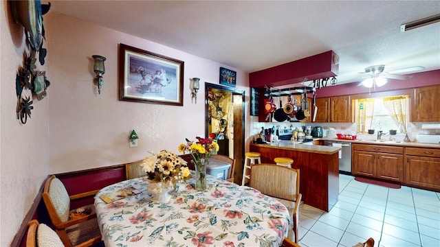 dining room featuring ceiling fan, sink, light tile patterned floors, and a textured ceiling