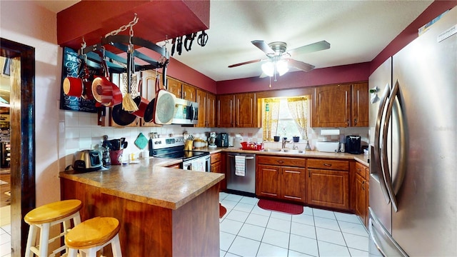 kitchen with sink, appliances with stainless steel finishes, tasteful backsplash, a kitchen bar, and kitchen peninsula