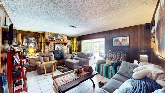 living room with wooden walls, a textured ceiling, a fireplace, light tile patterned flooring, and brick wall