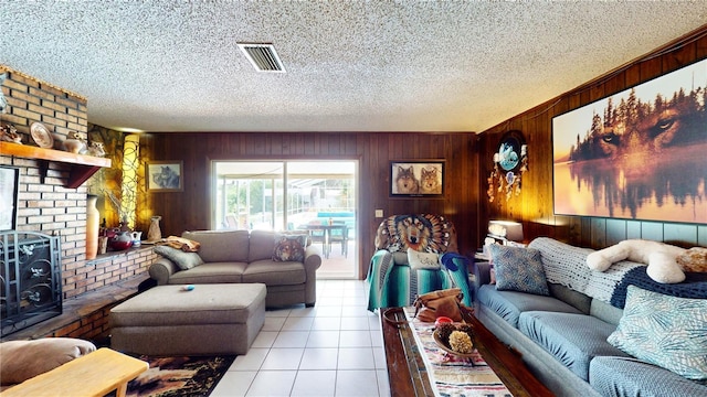 tiled living room featuring a wood stove, a textured ceiling, and wooden walls