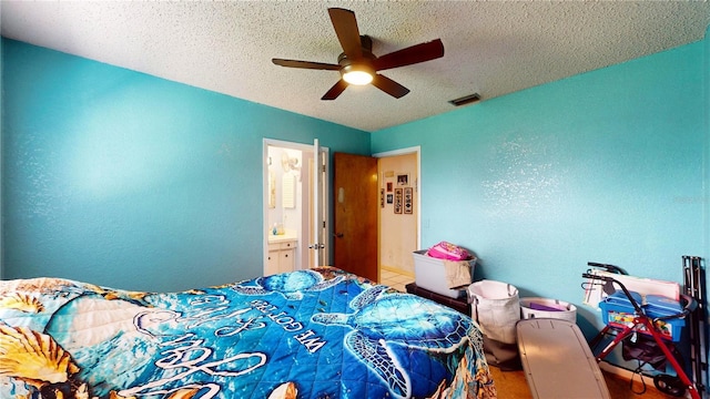 bedroom featuring ceiling fan, ensuite bathroom, and a textured ceiling