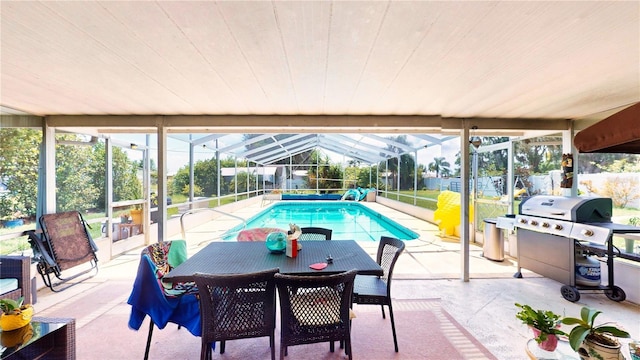 view of pool with area for grilling, glass enclosure, and a patio area