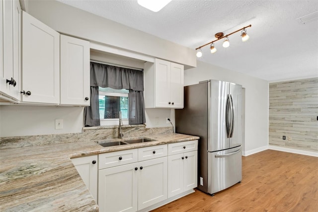 kitchen with white cabinets, stainless steel fridge, a textured ceiling, and sink