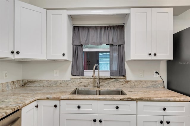 kitchen featuring white cabinets, light stone countertops, and sink