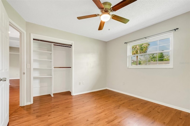 unfurnished bedroom featuring a closet, a textured ceiling, ceiling fan, and light hardwood / wood-style floors