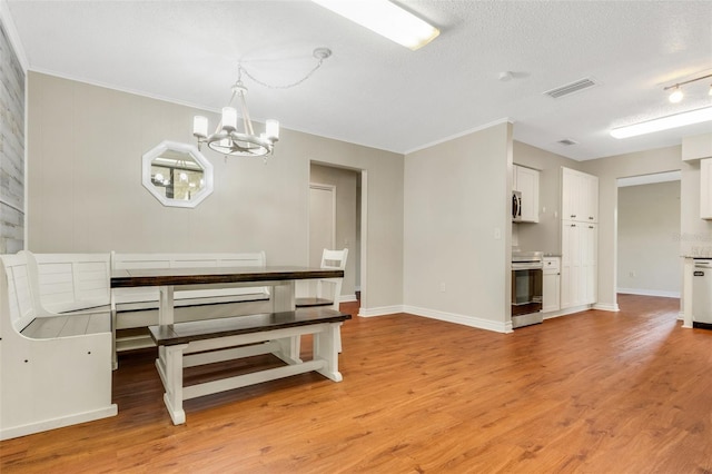 unfurnished dining area featuring ornamental molding, a textured ceiling, and light hardwood / wood-style flooring