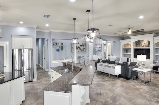 kitchen featuring white cabinets, sink, stainless steel fridge, dark stone countertops, and decorative light fixtures