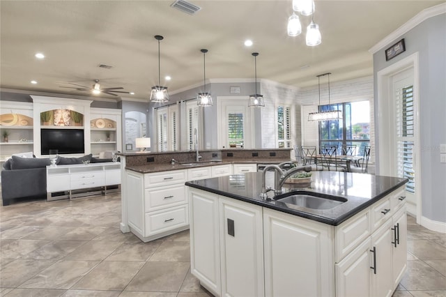 kitchen featuring sink, decorative light fixtures, ceiling fan, and an island with sink