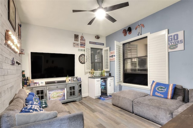 living room featuring light hardwood / wood-style floors, bar, beverage cooler, and ceiling fan